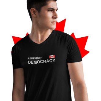 Person wearing a black Remember Democracy Canada statement clothing T-shirt with white text and a small Canadian flag, standing in front of a bold red maple leaf background.