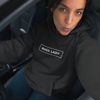 Woman wearing a black Boss Lady statement clothing hoodie with bold white text, taking a selfie inside a car.