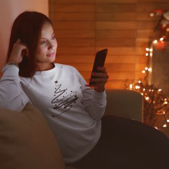 Person wearing a white Minimalistic Christmas statement clothing sweatshirt with a black abstract Christmas tree design.